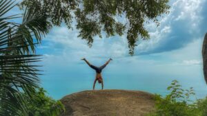 free photo of man performing handstand on seaside rock